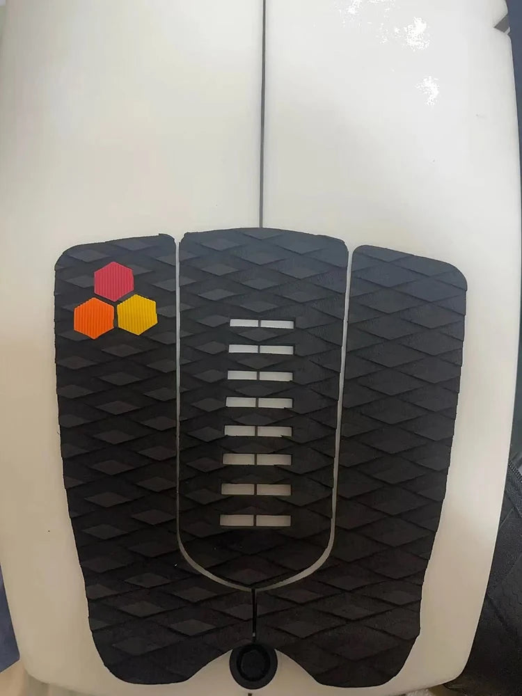 Close-up of black diamond grip, center slots and red, orange and yellow accents on the surfboard pad