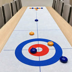 Tabletop Curling Game Set with orange and blue rollers spread along a target mat on a wooden dining table