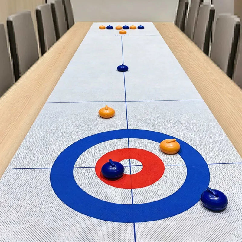 Tabletop Curling Game Set with orange and blue rollers spread along a target mat on a wooden dining table