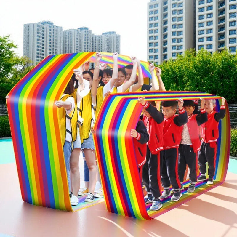 Team Building Race Mat: Adults in yellow vests and children in red jackets using rainbow loops outdoors.
