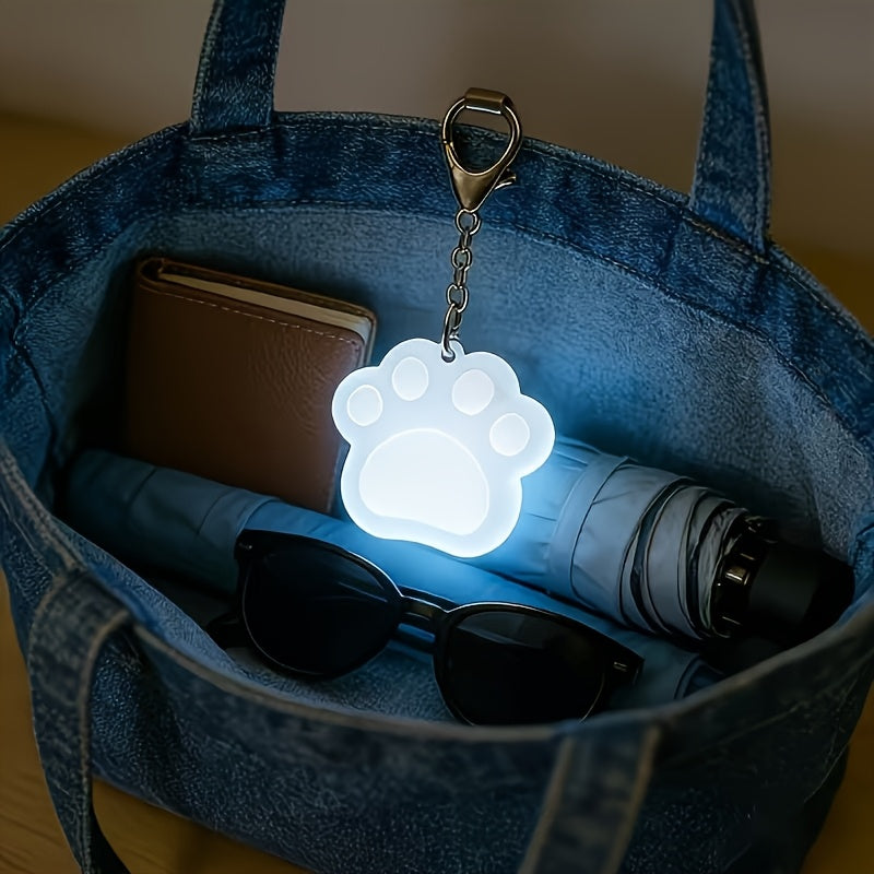 Touch Activated Bag Light — Paw shape glowing inside a denim tote beside sunglasses and a wallet.