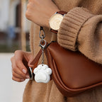 Touch Activated Bag Light — Paw shape hanging from a brown handbag beside a knitted sleeve.
