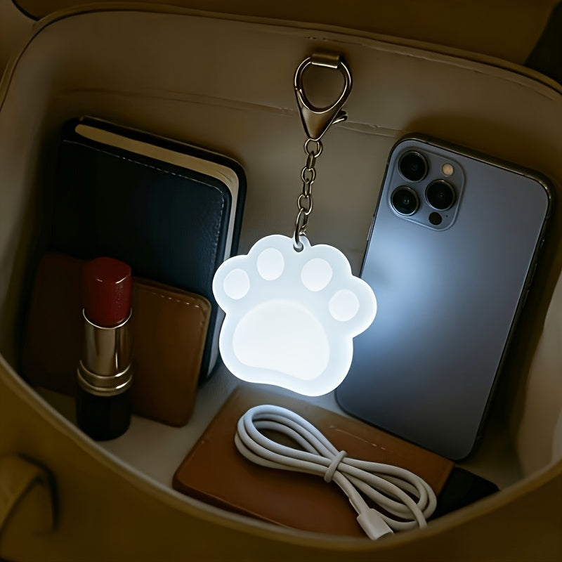 Touch Activated Bag Light — Paw shape glowing inside a handbag beside a phone and wallet.