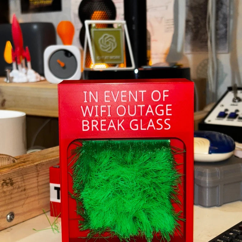 Touch Grass Meme Box standing on a desk with red casing and green grass beneath the Wi-Fi outage message
