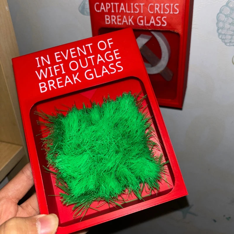 Touch Grass Meme Box held in one hand with its Wi-Fi outage message and green grass visible