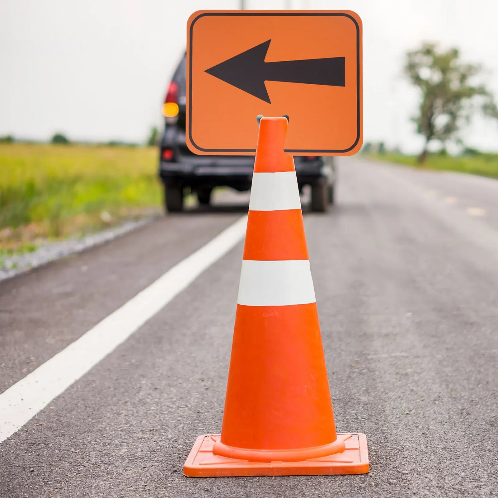 Traffic Cone Arrow Sign mounted on an orange cone with a left arrow guiding vehicles along a roadside
