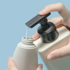 Travel Squeeze Bottle Set close-up of a travel bottle being filled through its open neck from a larger pump bottle.