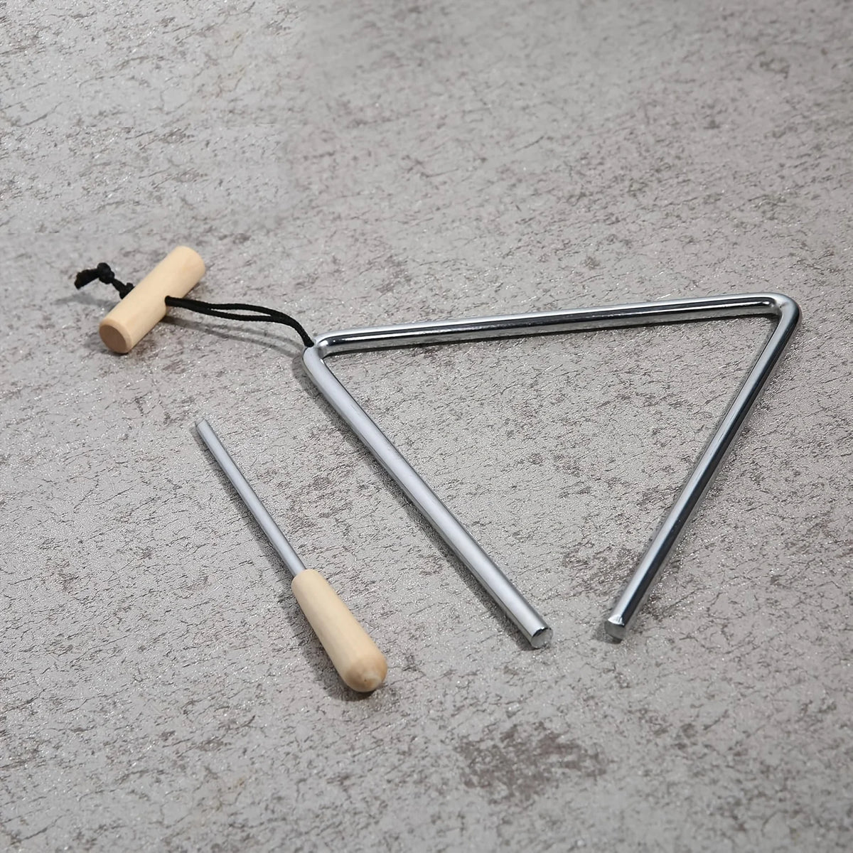 Triangle Instrument Set angled on a textured gray surface, showing its open corner, cord and beater