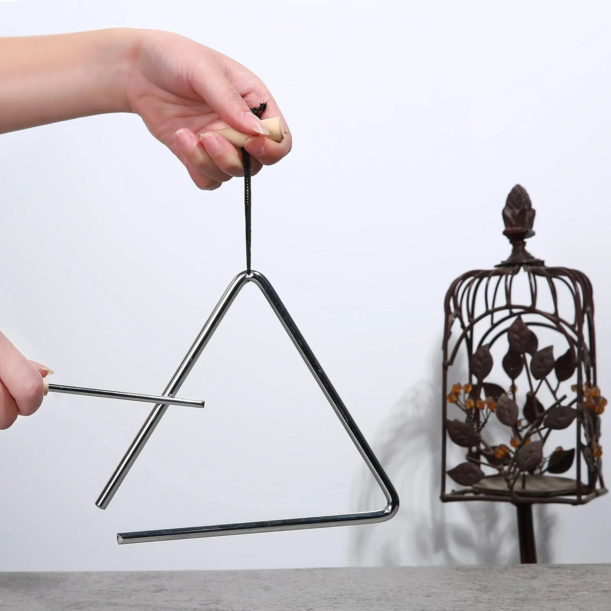 Triangle Instrument Set held for practice beside a decorative lantern, showing the suspension handle