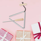 Triangle Instrument Set on a pink background with wrapped gifts and the beater across the triangle