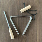 Triangle Instrument Set with silver triangle, black suspension cord and pale handles on a wooden table