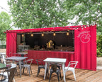 Red container café exterior example with a wide service counter, string lights, and patio tables