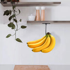 Under-Cabinet Banana Hook holding a banana bunch beneath a wood shelf in a minimalist kitchen