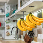 Two Under-Cabinet Banana Hooks holding separate banana bunches beneath a lit kitchen cabinet