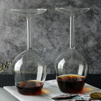 Two clear Upside Down Wine Glasses with dark drinks displayed side by side