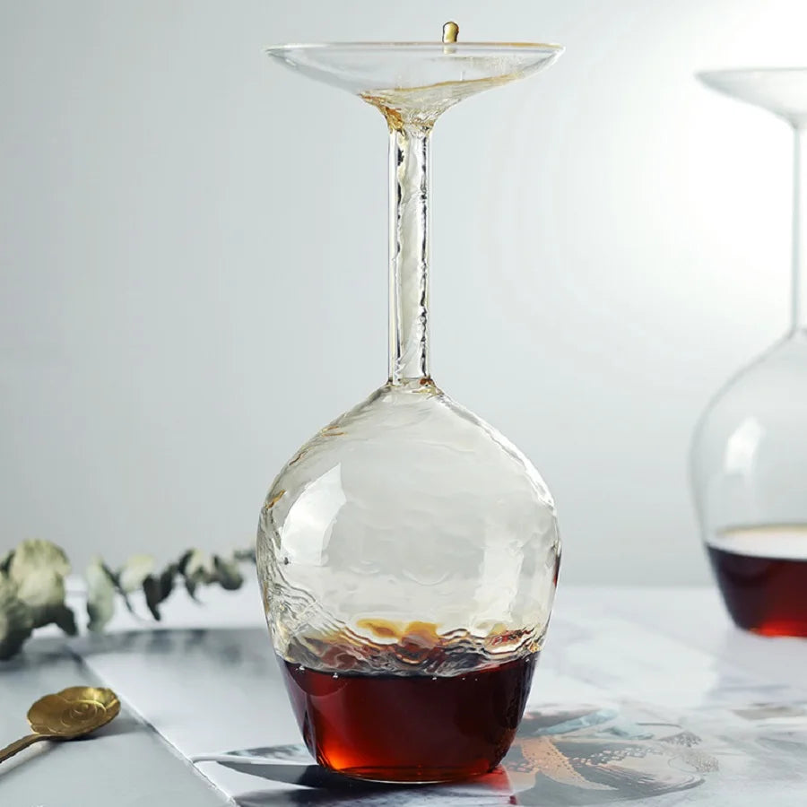 Drink flowing through the upper opening and hollow stem into Upside Down Wine Glass