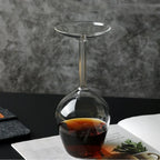 Upside Down Wine Glass standing on a printed page with a dark drink inside