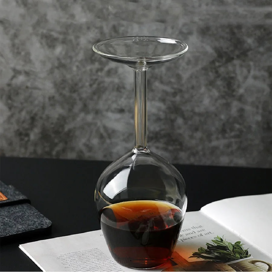 Upside Down Wine Glass standing on a printed page with a dark drink inside