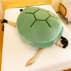 Wearable Turtle Shell Pillow in green used as an oversized cozy cushion on a bed
