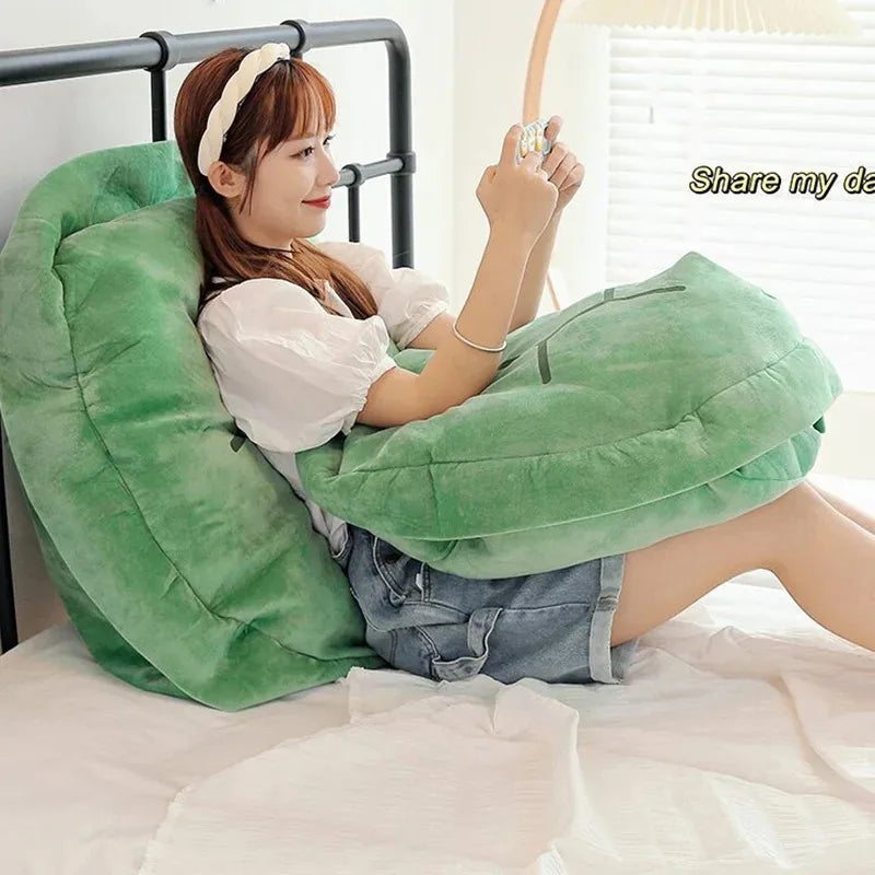 Wearable Turtle Shell Pillow in green supporting a person reading comfortably on a bed