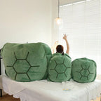 Wearable Turtle Shell Pillow in three green sizes lined up across a bedroom sofa