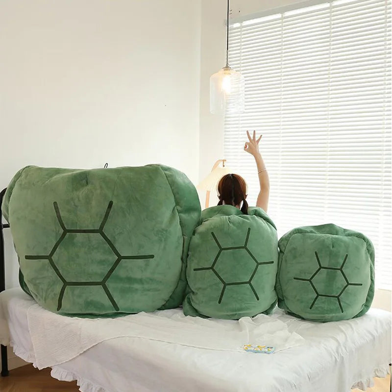 Wearable Turtle Shell Pillow in three green sizes lined up across a bedroom sofa