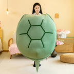 Wearable Turtle Shell Pillow in green displayed by a person standing in a bright bedroom