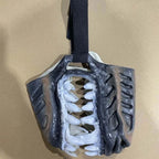 Side view of Werewolf Fangs Dog Mask without blood hanging from its strap against a brown background
