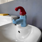 Wiggly Hat Sink Faucet close-up of the blue face and red hat installed on a curved white bathroom sink.