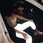 Women’s Reflective Joggers reflecting light while worn with a white crop top in an open car doorway
