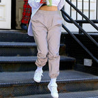 Women’s Reflective Joggers modeled on metal steps with a gathered waistband, tapered legs, and white sneakers