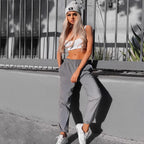 Women’s Reflective Joggers modeled beside a gray wall with a white crop top, knit beanie, and sneakers