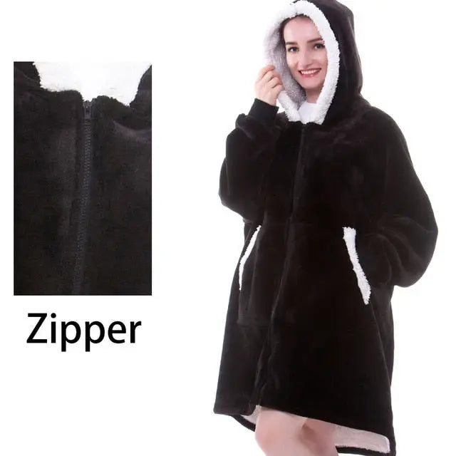 Black oversized hoodie blanket with white sherpa lining and front zipper shown on model against white background