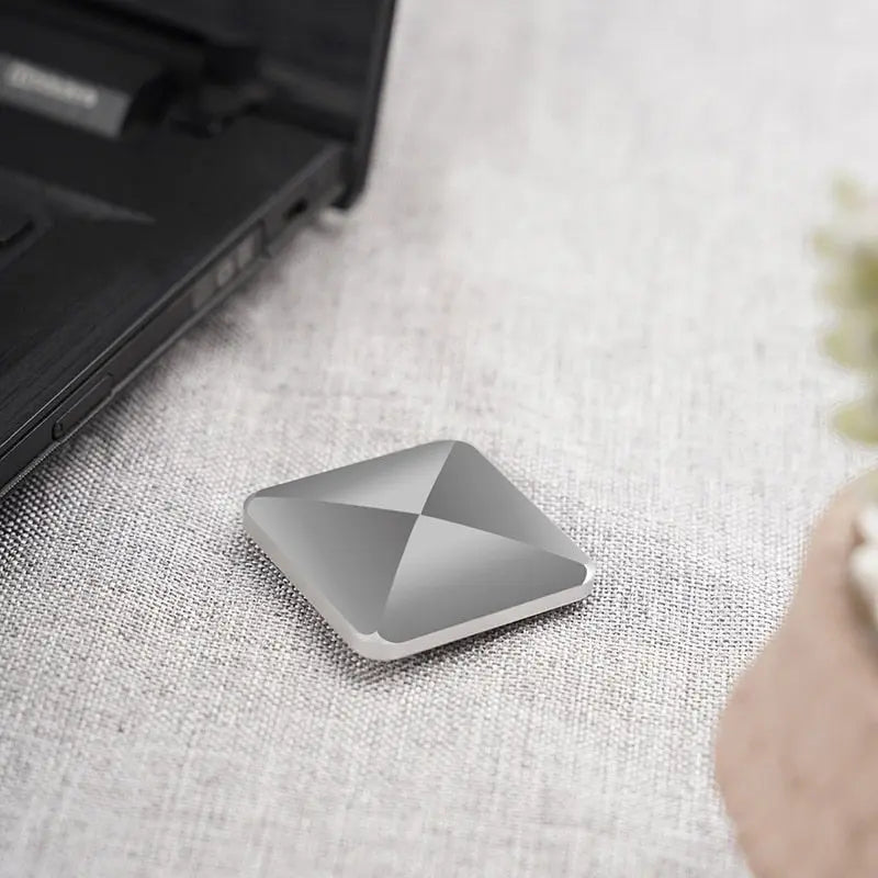 HexFlip fidget toy in metallic silver finish on light grey fabric surface, featuring geometric pyramid design