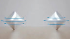 HexFlip fidget toy in silver metal with blue spinning rings demonstrated in flipping motion on beige surface