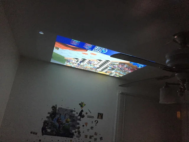 HighPeak MiniProjector projecting a colorful image on a bedroom ceiling creating a cozy home theater atmosphere.