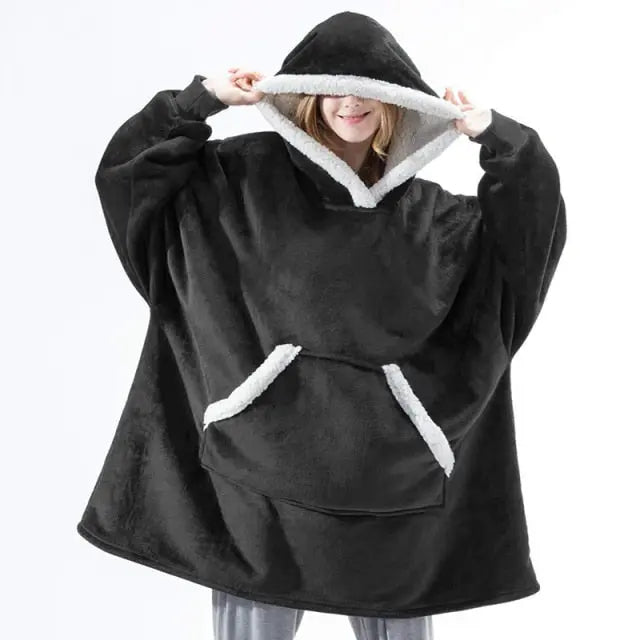 Oversized Hoodie Blanket in black with white sherpa lining, shown worn with front kangaroo pocket and large hood design