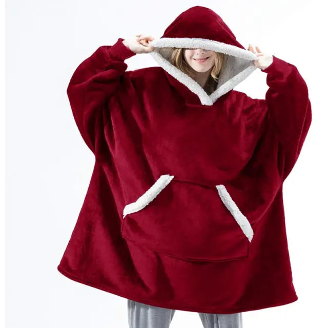 Oversized Hoodie Blanket in deep red with sherpa lining and kangaroo pocket, shown cozy and relaxed on person at home