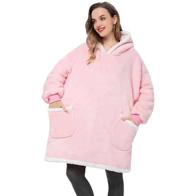 Oversized Hoodie Blanket in soft pink with sherpa lining, front pockets, and cozy fit worn by person in casual setting