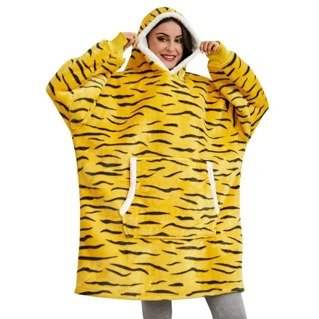 Oversized Hoodie Blanket in tiger print pattern with sherpa lining, white trim and front kangaroo pocket shown on cozy home setting