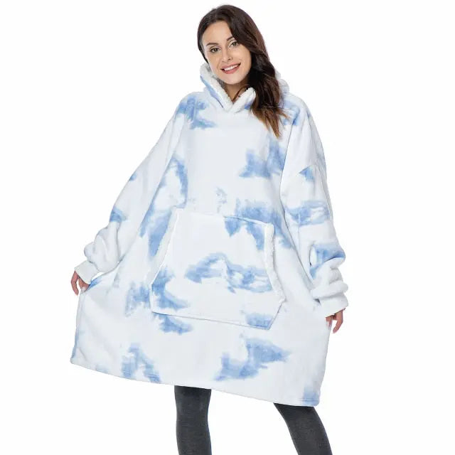 Oversized Hoodie Blanket in white and blue tie-dye pattern with kangaroo pocket and plush sherpa lining, shown worn as cozy outerwear