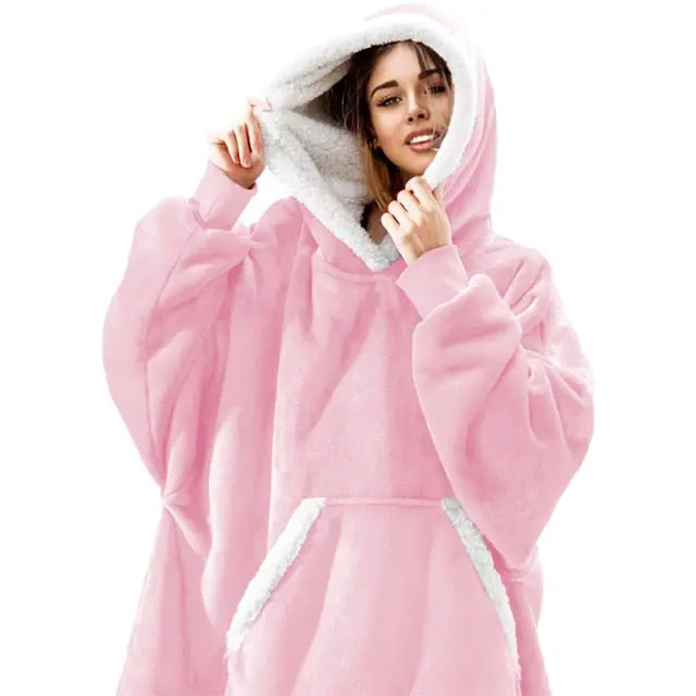 Pink oversized hoodie blanket with sherpa lining and front pocket, shown worn as cozy wearable blanket